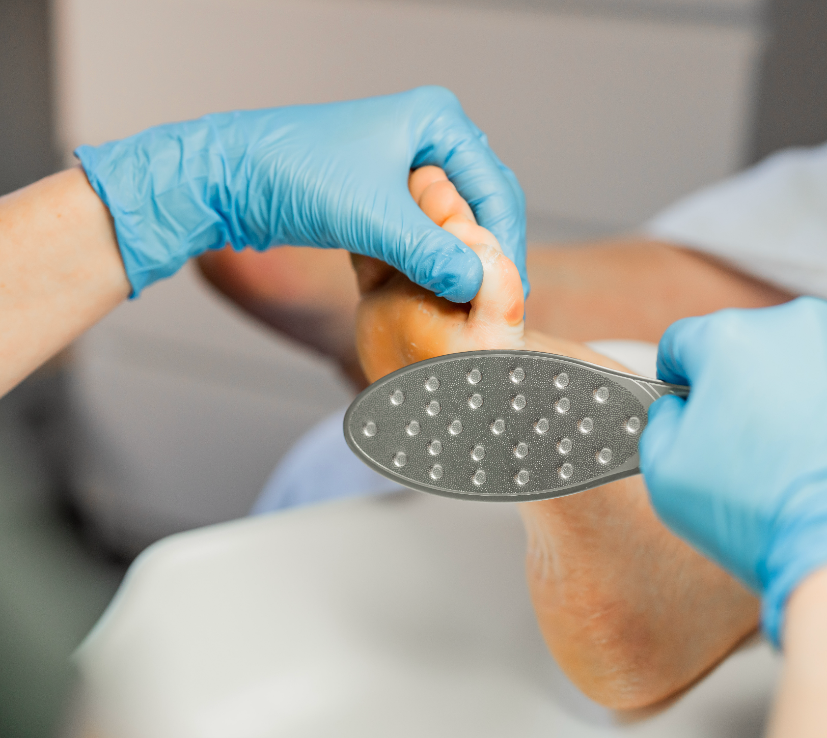 Close-up of professional foot care using Imperial Feet stainless steel foot file to exfoliate callused skin during pedicure treatment.